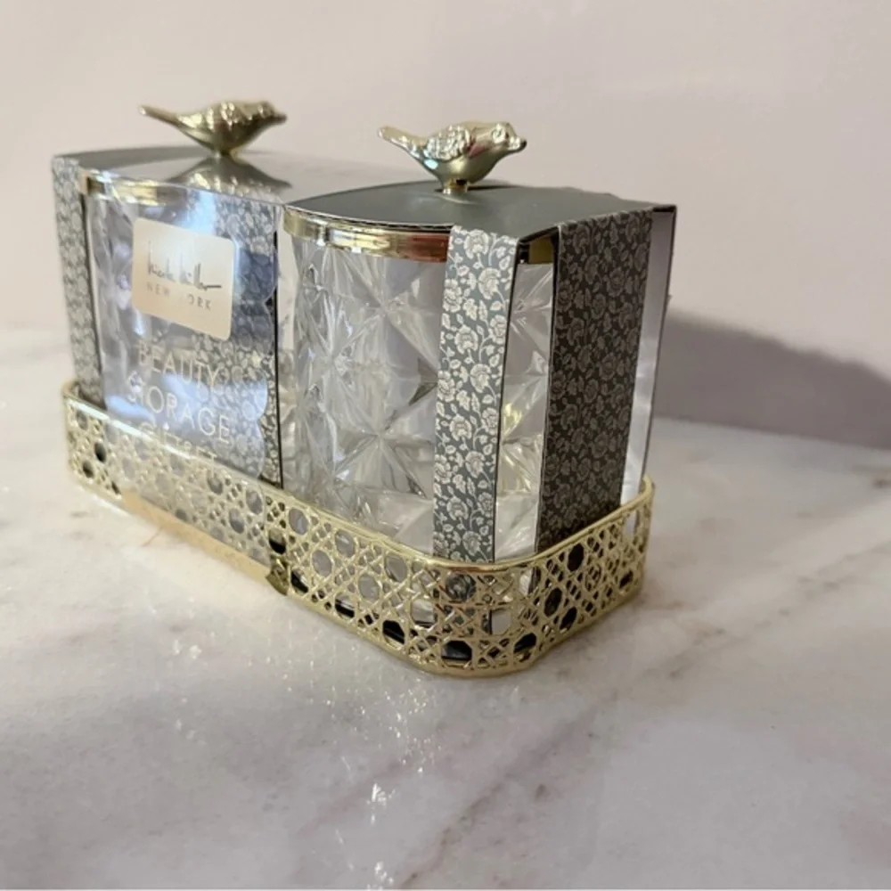 two-piece glass storage jar set with a gold bird lid and decorative tray.